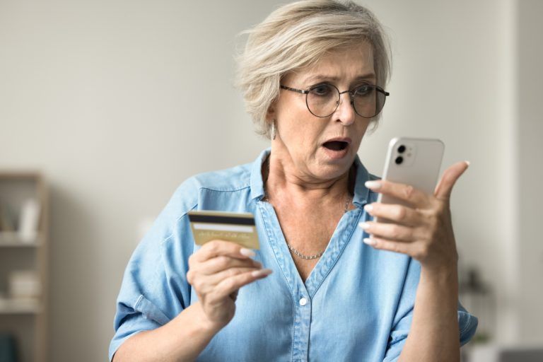 Shocked,Concerned,Mature,Woman,In,Glasses,Holding,Credit,Card,,Staring